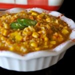 Vegan Creamed corn in a white pie dish with a red and white casserole dish behind it.