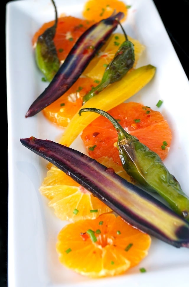 Colorful Citrus Carrot Salad with blistered shishito peppers on a white plate