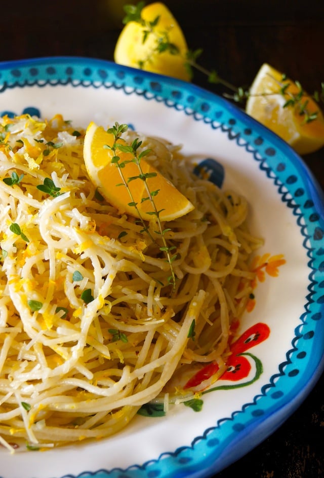 Meyer Lemon-Thyme Spaghetti in a pretty blue-rimmed ceramic plate with lemon wedges and thyme sprigs