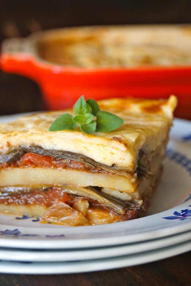 slice of Potato Moussaka on a small stack of plates, from Raghavan Iyer's newest cookbook, Smashed, Mashed, Boiled and Baked, this delicious, vegetarian Moussaka recipe is packed with warm spices, tender slices of potato and caramelized eggplant. 