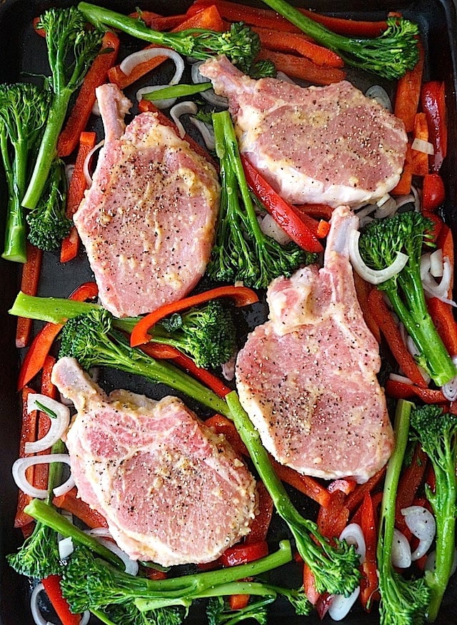 Four raw pork chops with marinade, broccolini and red peppers, for Sheet Pan Miso Glazed Pork Chops.