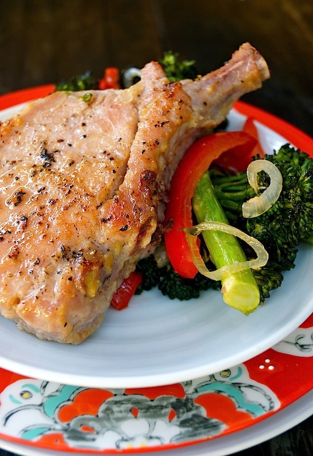 One pork chop from on a white and red plate from Sheet Pan Miso Glazed Pork Chops with Broccolini.