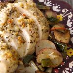 Deep purple plate with painted edges with sliced Parmesan-Crusted chicken breast and roasted potatoes.