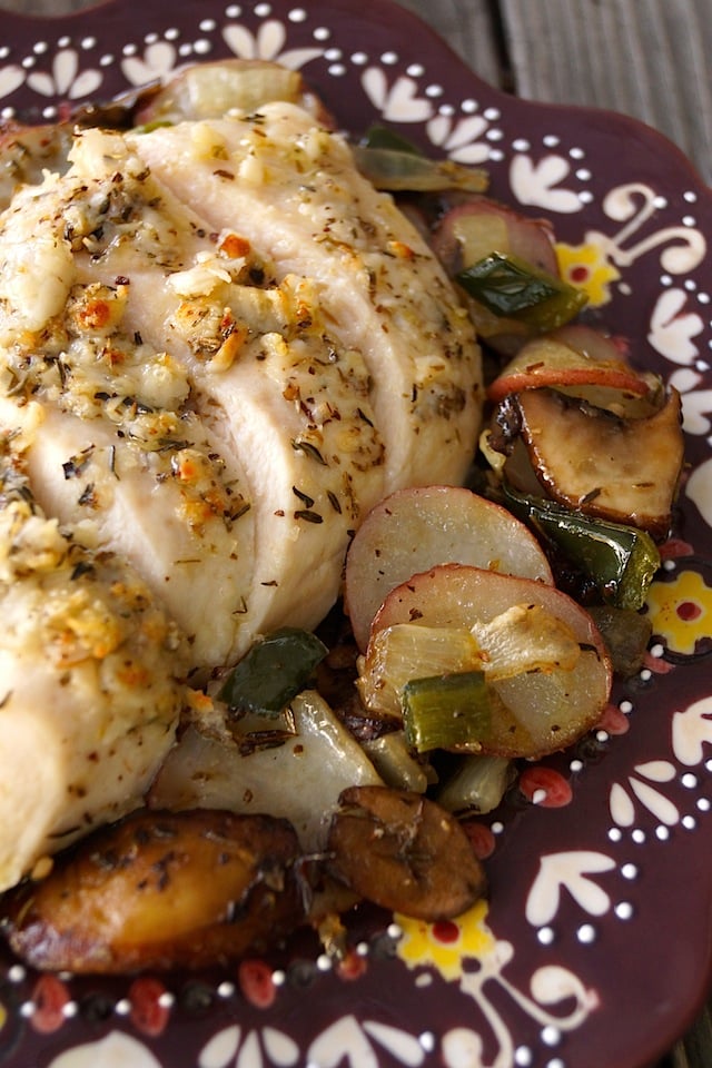 Close up of Sheet Pan Parmesan-Herb Chicken with Poblano Potatoes, sliced on a burgandy plate.