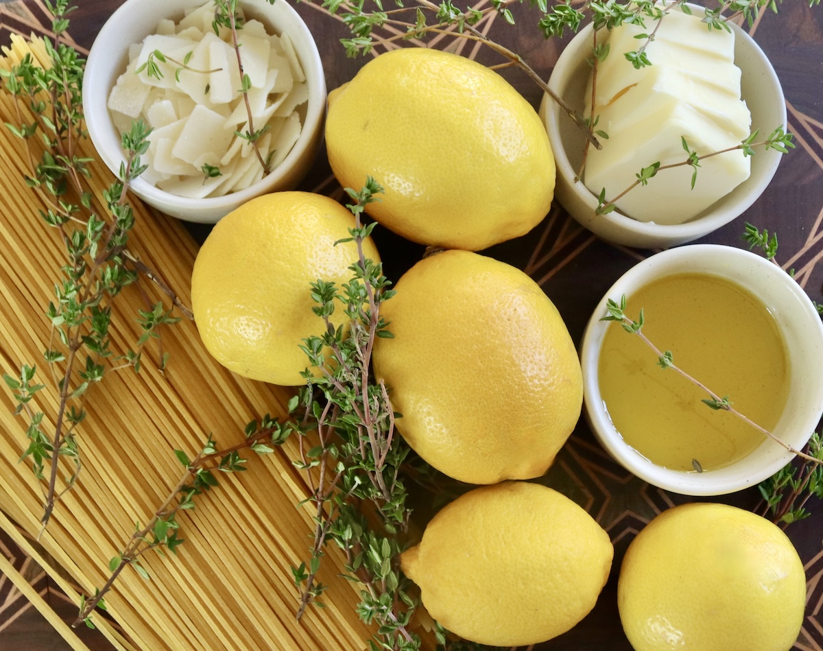 Meyer-Lemon-Spaghetti-with-Thyme A few lemons with fresh thyme, dry spaghetti, and tiny white bowls of butter, Parmesan cheese and olive oil.