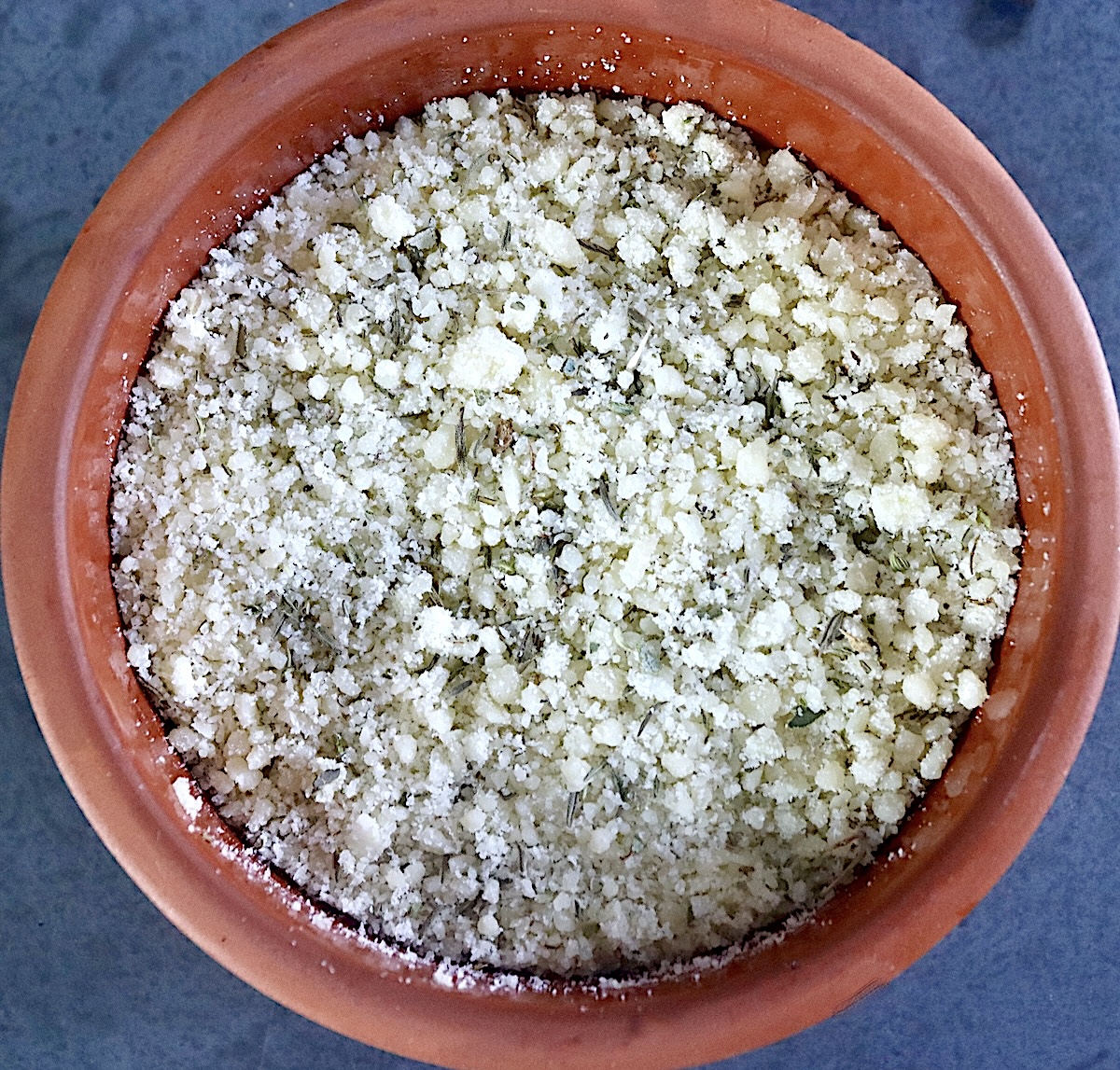Terra cotta bowl filled with parmesan-herb mixture.