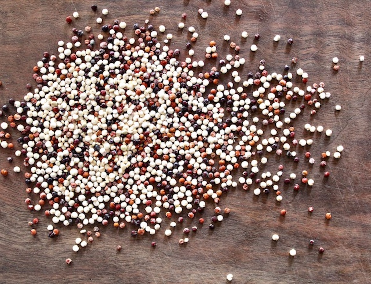 Vegetable-Lemon-Quinoa-Recipe Raw multi-colored quinoa spread out on a cutting board.