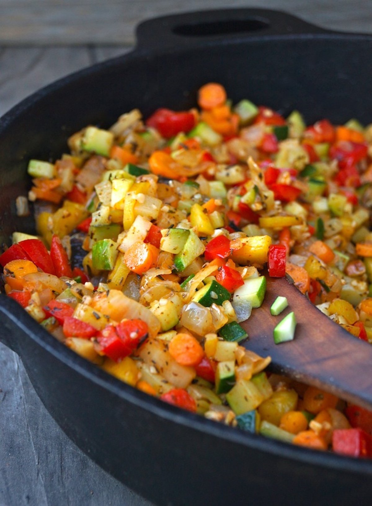 Vegetable-Lemon-Quinoa-Recipe Skillet full of chopped colorful vegetables with a wooden spatula.