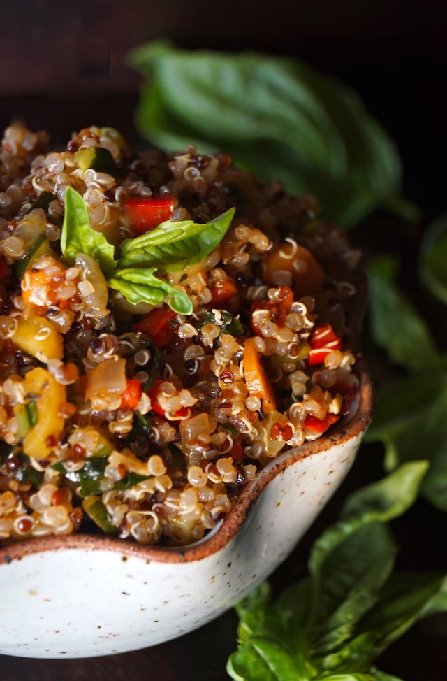 Smoky Lemon Vegetable Quinoa Recipe, with bright orange carrot round, red peppers and absil leaves on top 