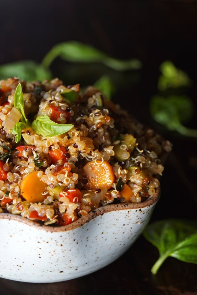 Quinoa with vegetables, bright orange carrot round, red peppers and absil leaves on top 