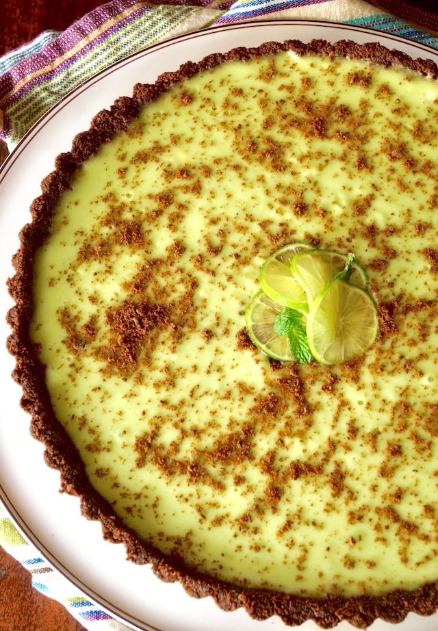 Thin Mint Key Lime Tart on a round, white platter with a striped cloth beneath it.