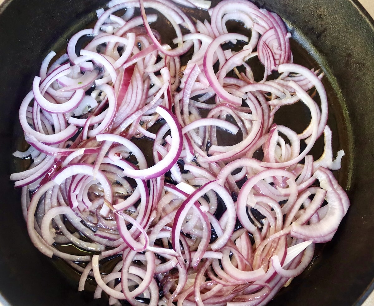 Lamb-Lasagna-Recipe Cast iron skillet with sliced, raw red onions.