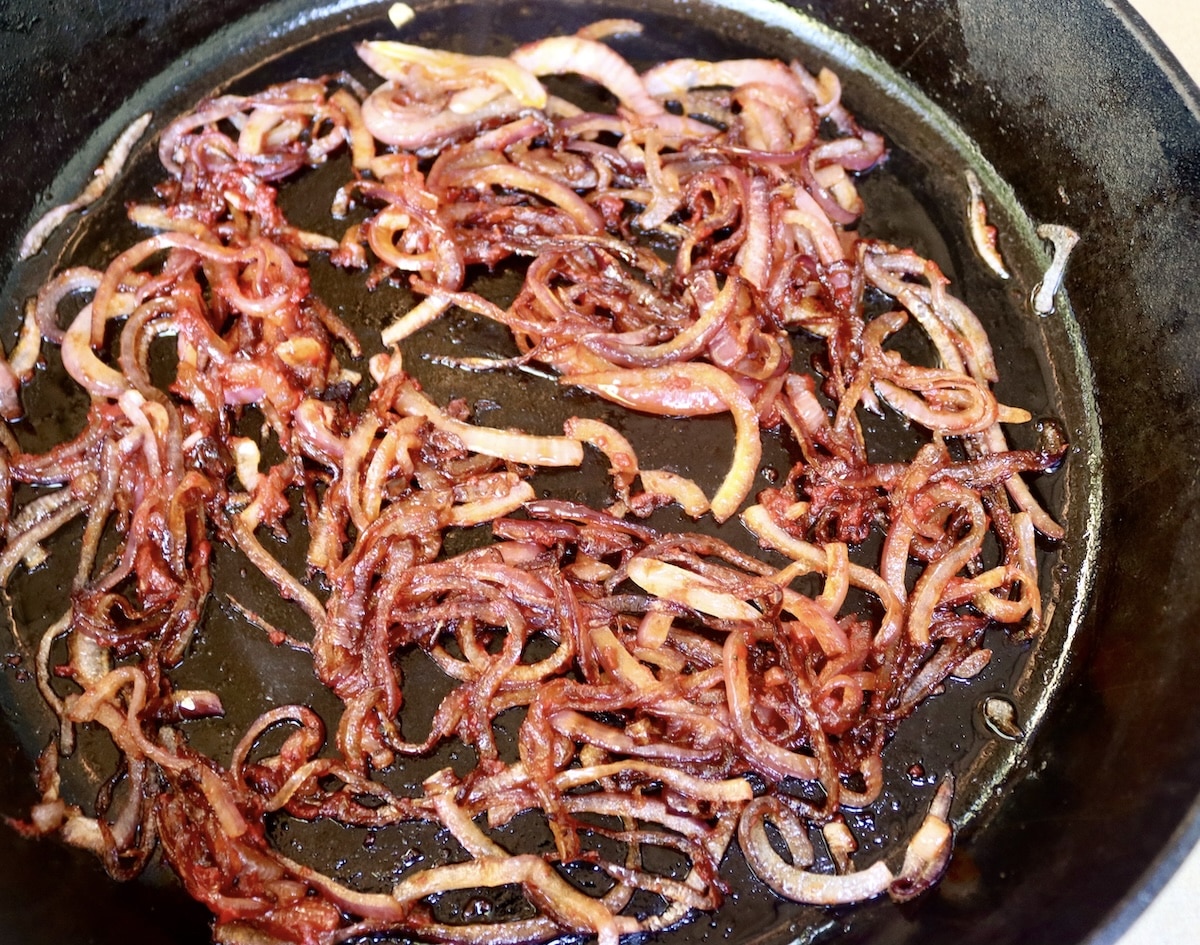 Lamb-Lasagna-Recipe Cast iron skillet with sliced, browned red onions and tomato paste.