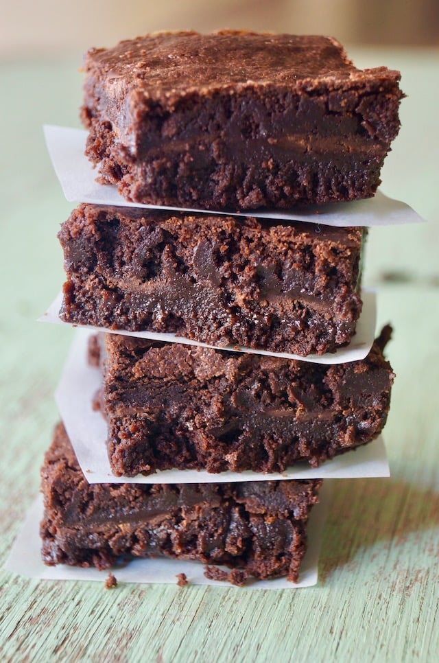 Stack of four After Eight Chocolate Mint Brownies with parchment between each one