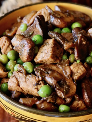 Pork and mushroom stew in a deep gold bowl with a black rim.