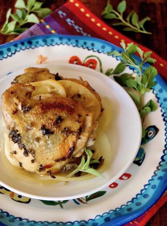 Butter Braised Chicken with Fresh Oregano on a pretty colorful ceramic plate with fresh oregano sprigs