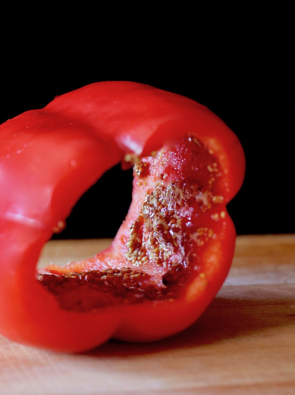 one hollowed out red bell pepper on cutting board
