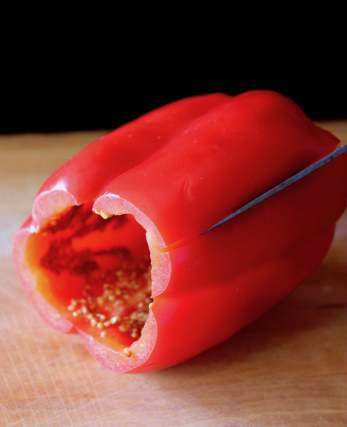 red bell pepper being sliced on cutting board