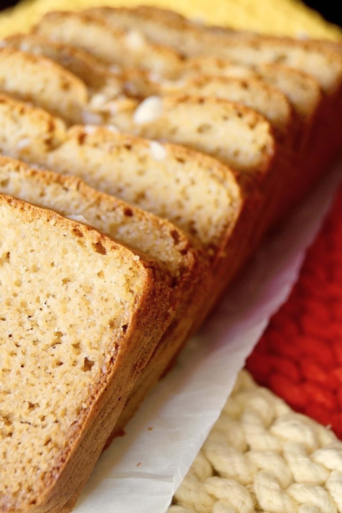 Sliced macadamia bread on parchment paper, with chopped macadamia nuts on top.