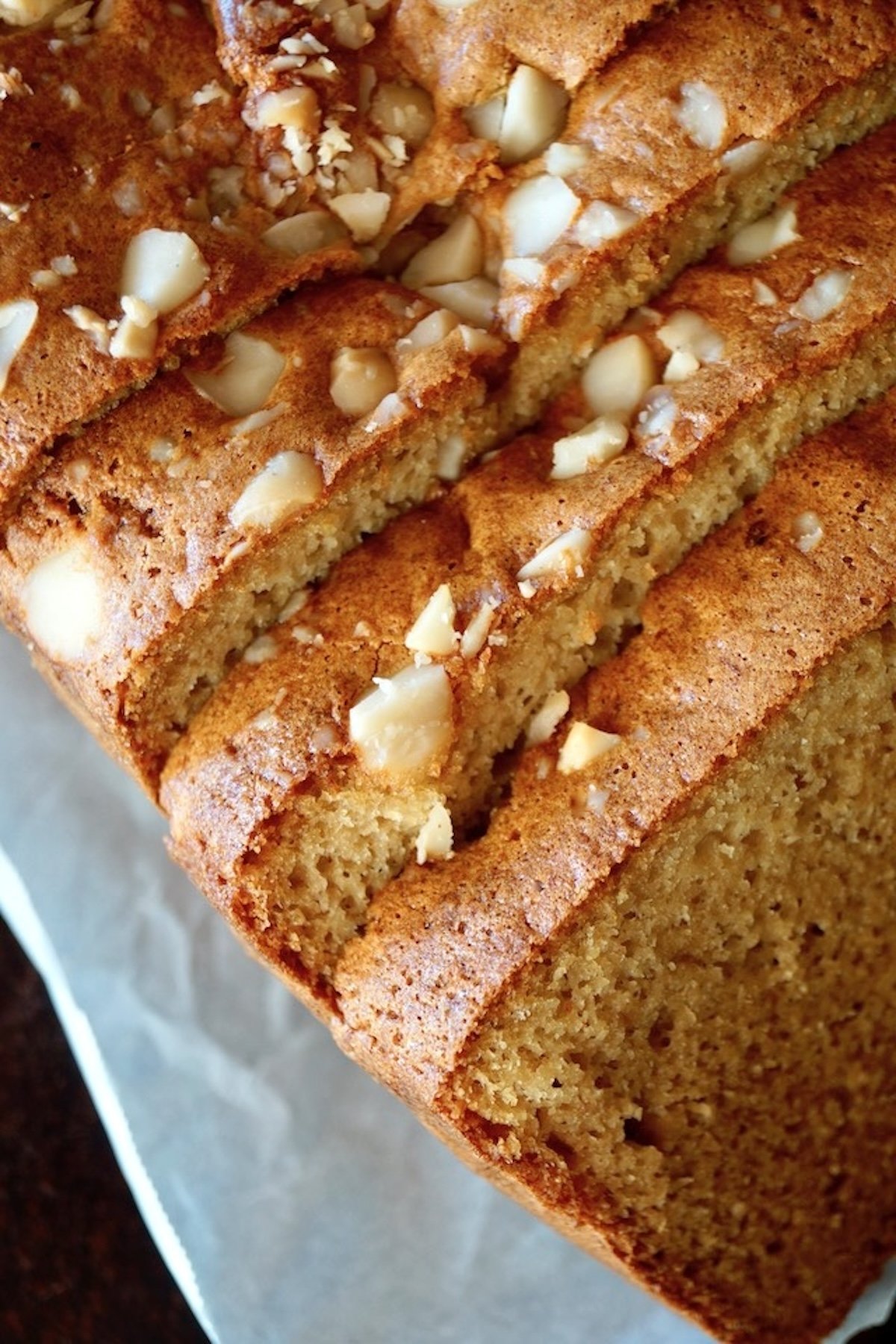 Sliced macadamia bread on parchment paper, with chopped macadamia nuts on top.