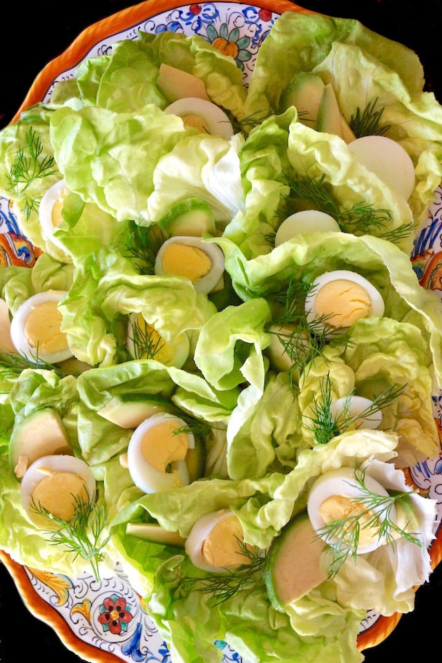 Lettuce and hard boiled egg slices on a gold-rimmed platter.