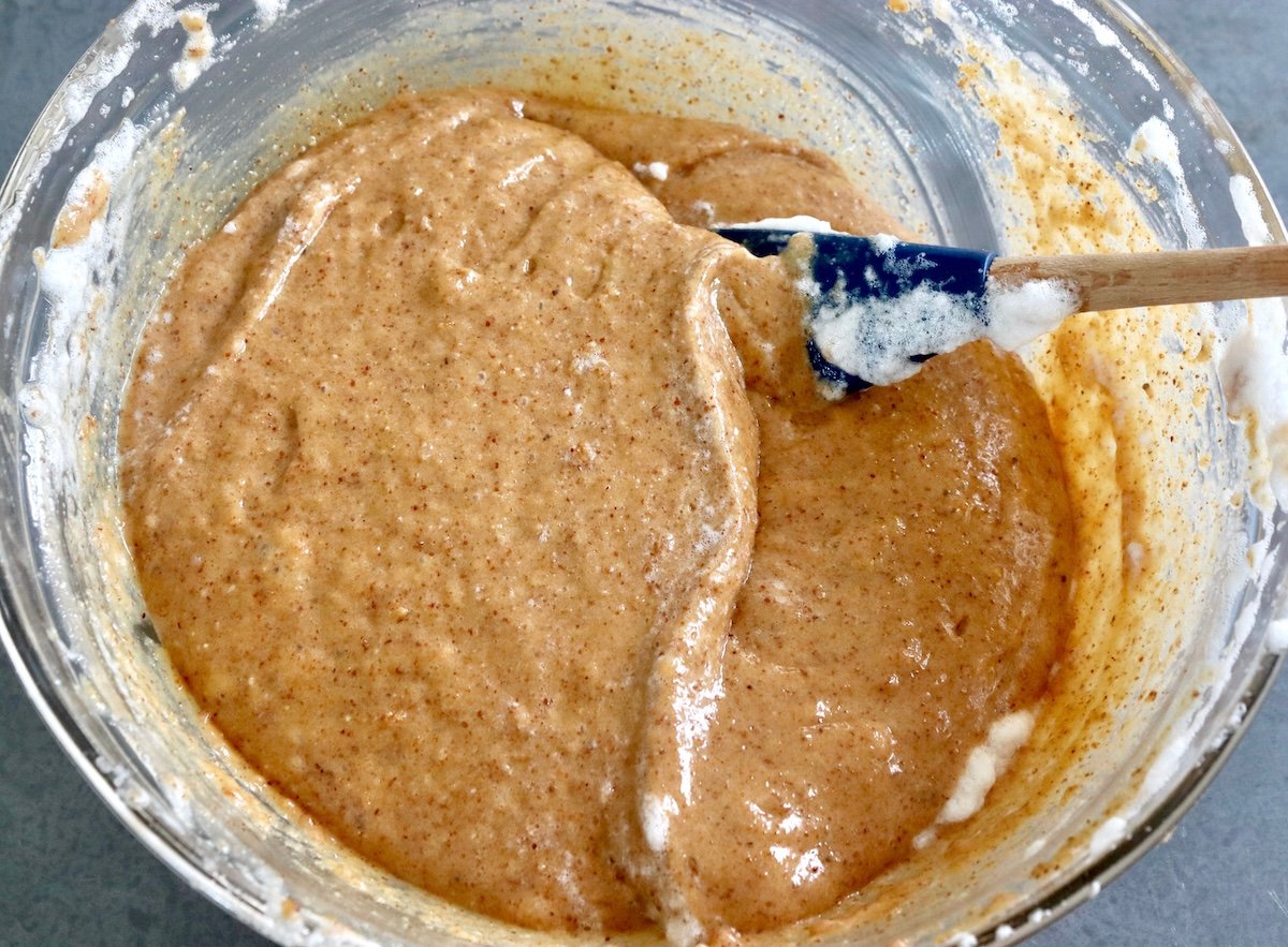 Smooth, mixed almond butter bread batter, in a glass bowl with a spatula.
