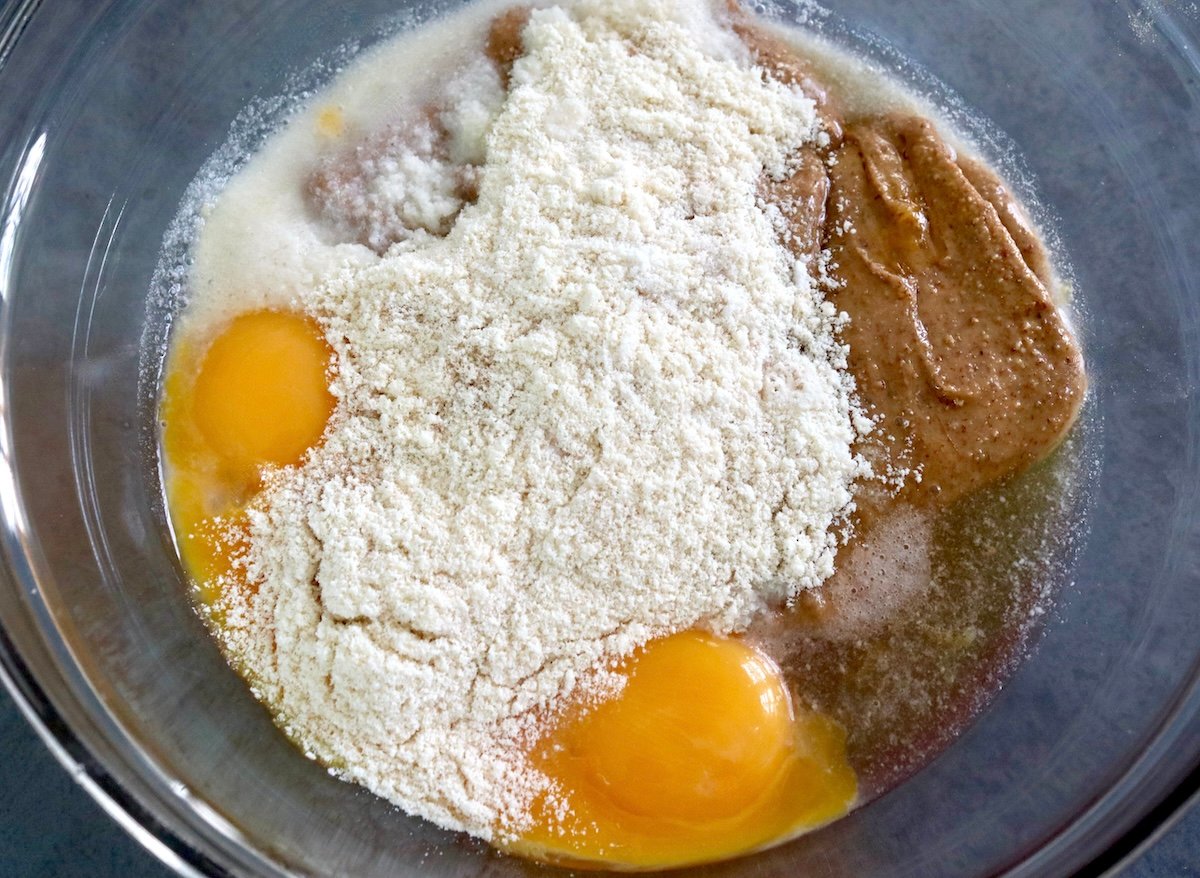 Glass bowl with coconut flour, almond butter and egg yolks, not mixed.
