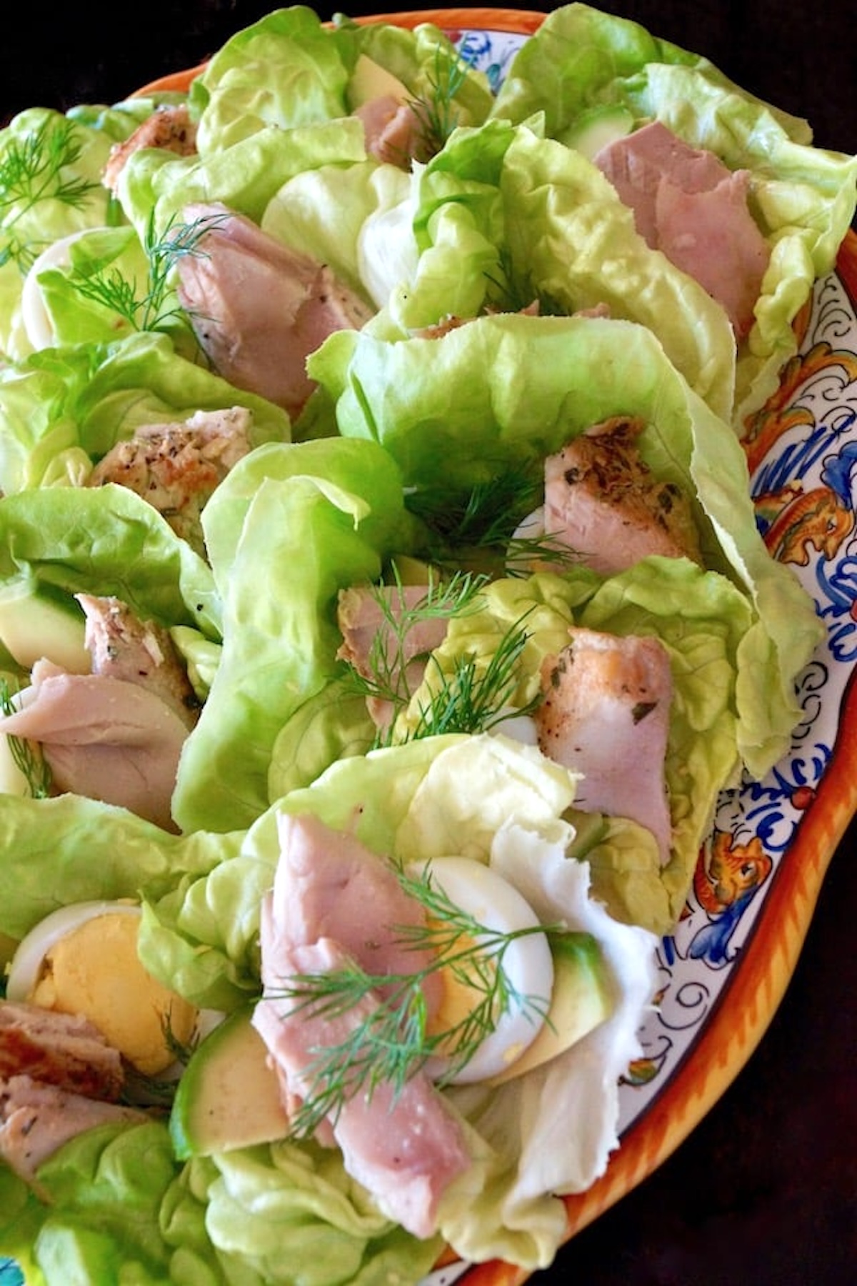 Nicoise Salad Cups Italian painted plate with about a dozen small butter lettuce cups, filled with tuna and egg.