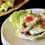 Three stacked white plates with a nicoise sala cup on top with a dill sprig.