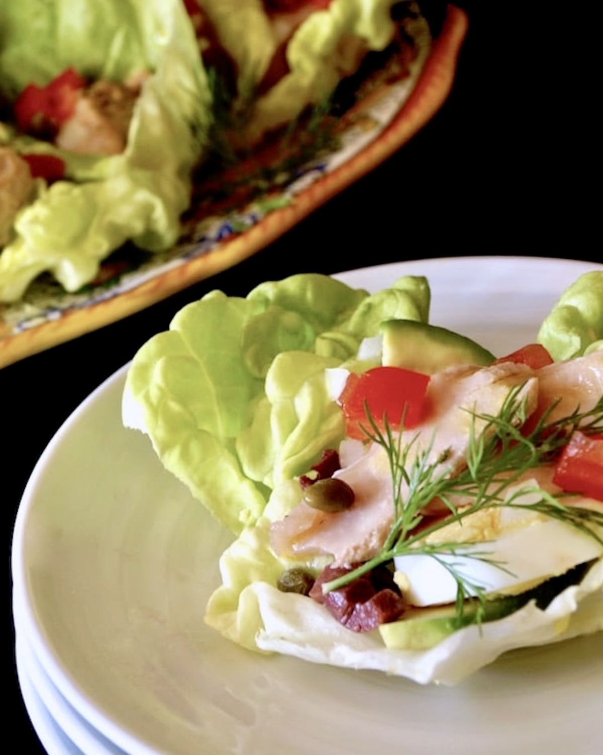 Nicoise Salad Cups Three stacked white plates with a nicoise salad cup on top with a dill sprig.
