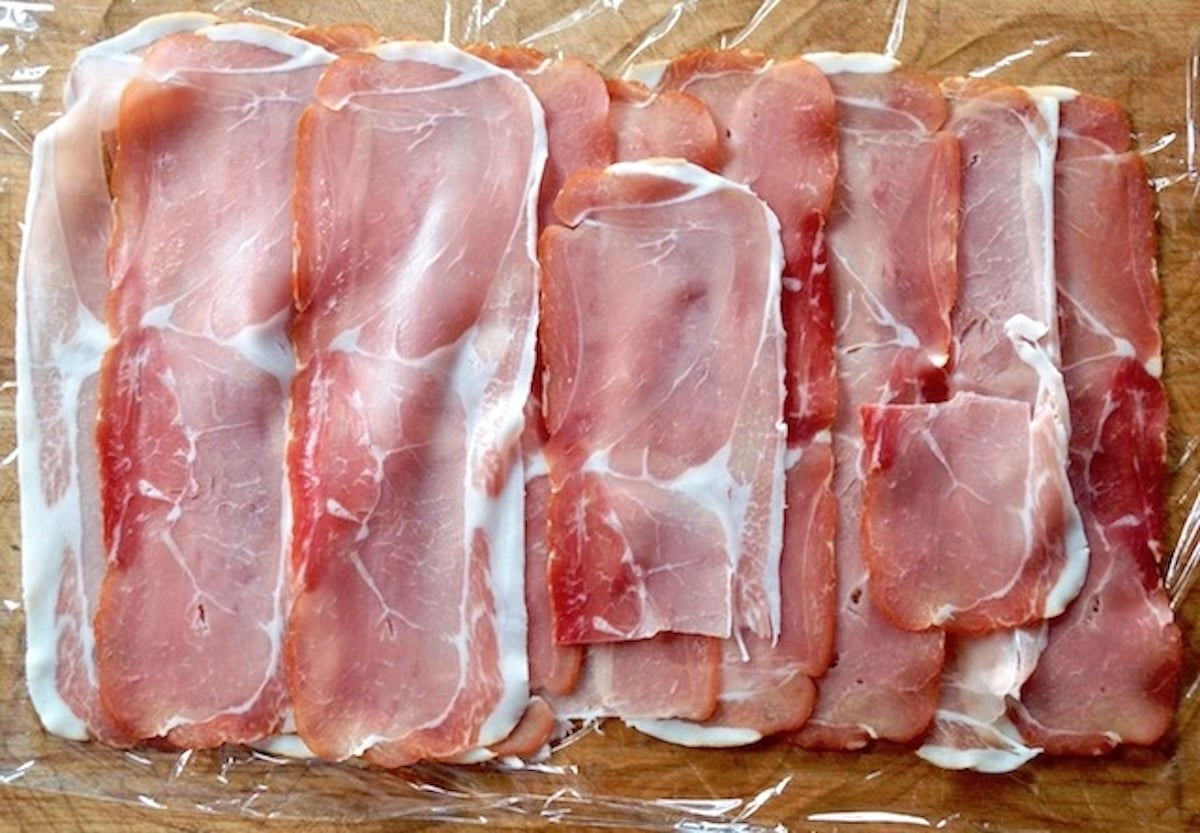 Layer of thin prosciutto slices to form a rectangle on plastic wrap.