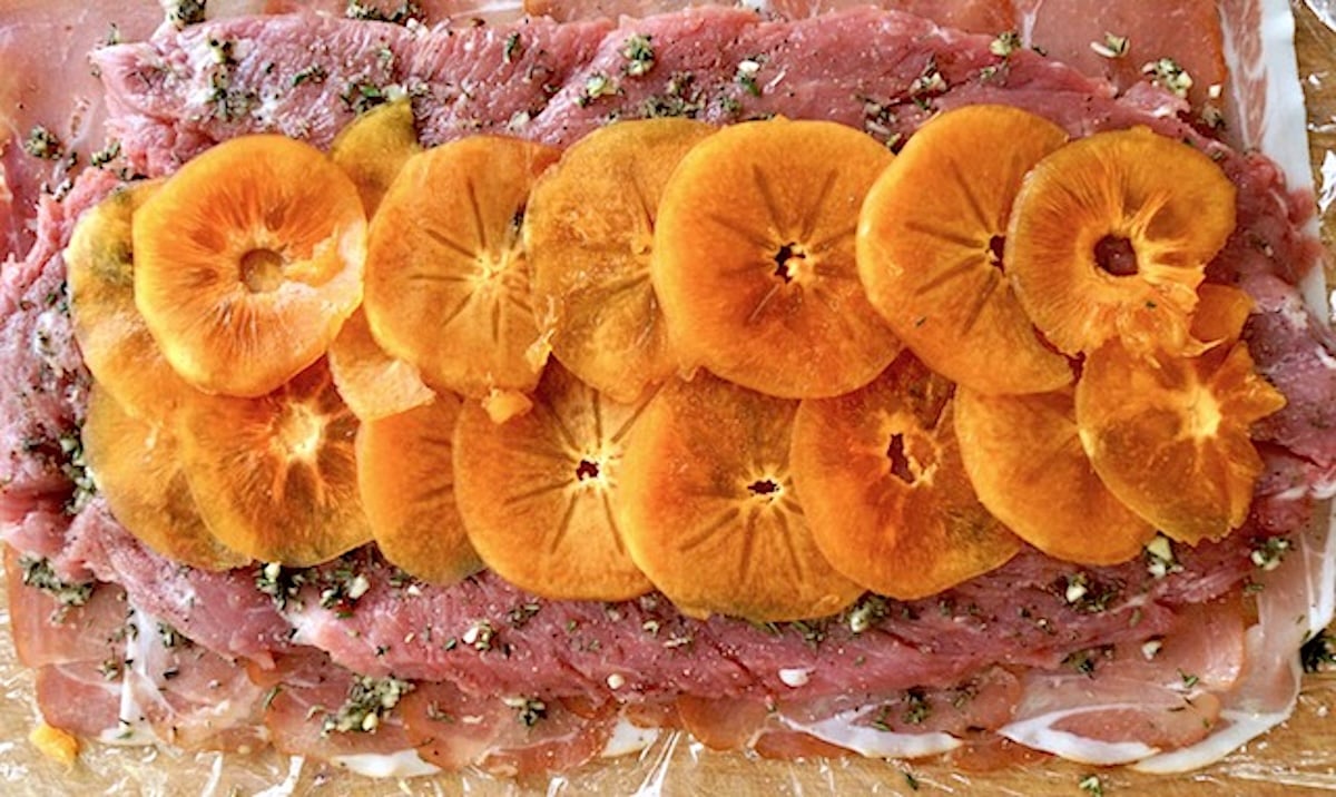 Layer of thin prosciutto slices to form a rectangle, with a butterflied pork tenderloin on top, sprinkled with fresh herbs and topped with thin slices of persimmon.