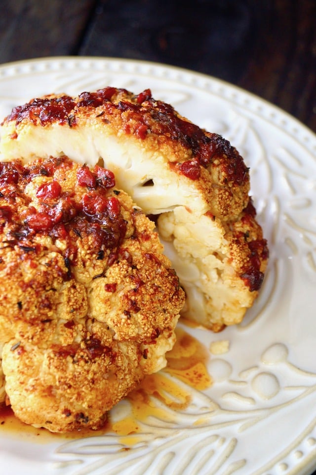 small whole roasted cauliflower, cut in half with light red pepper sauce over it