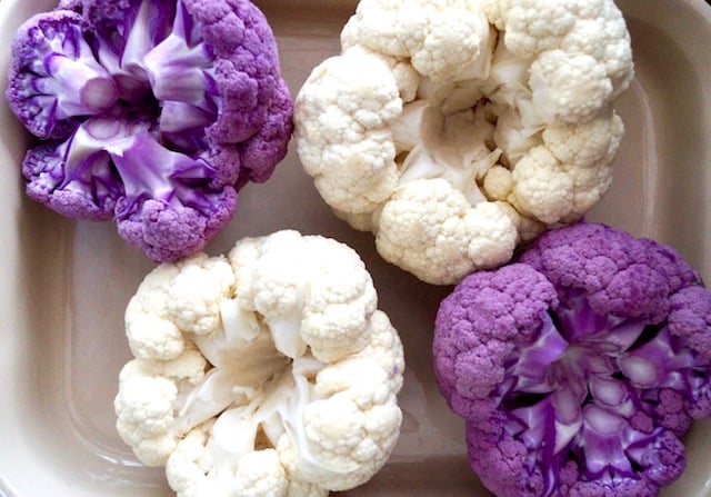 2 purple raw and 2 white raw cauliflower, rooot side up in a baking dish