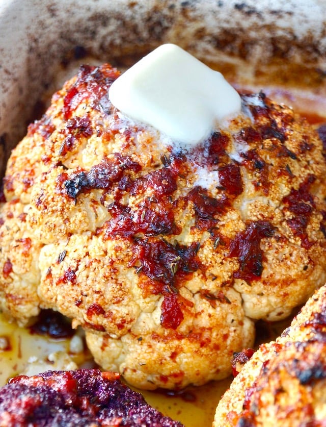 whole roasted cauliflower with bits of red pepper and light red sauce and dab of butter