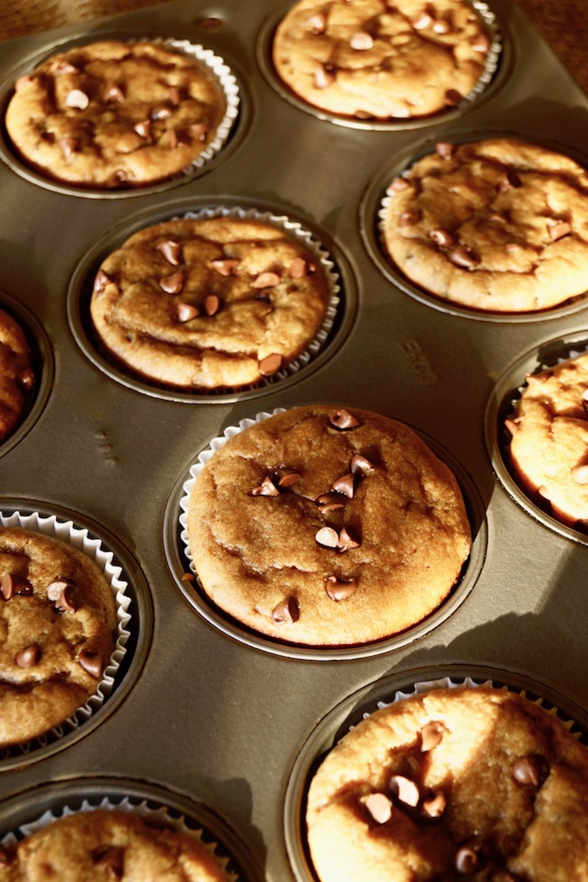 Peanut Butter Banana Muffins in the pan with pretty shadows.