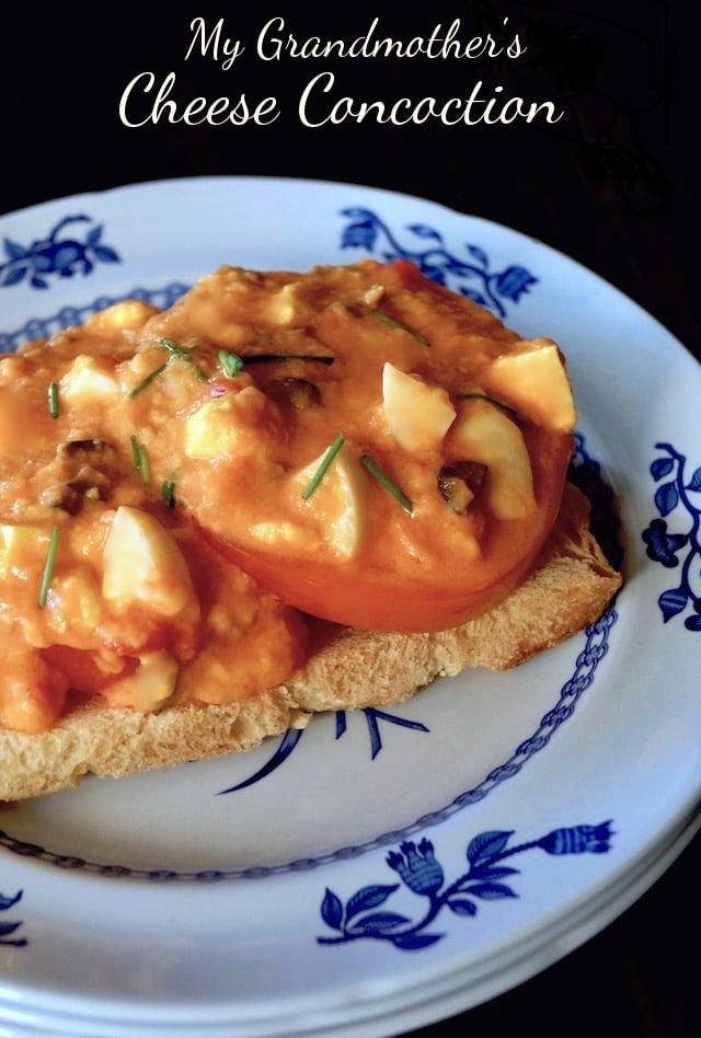 toast with tomato slices and melted cheese mixture on top, on white plate with blue flowers, with text "my Grandmother's Cheese Concoction"