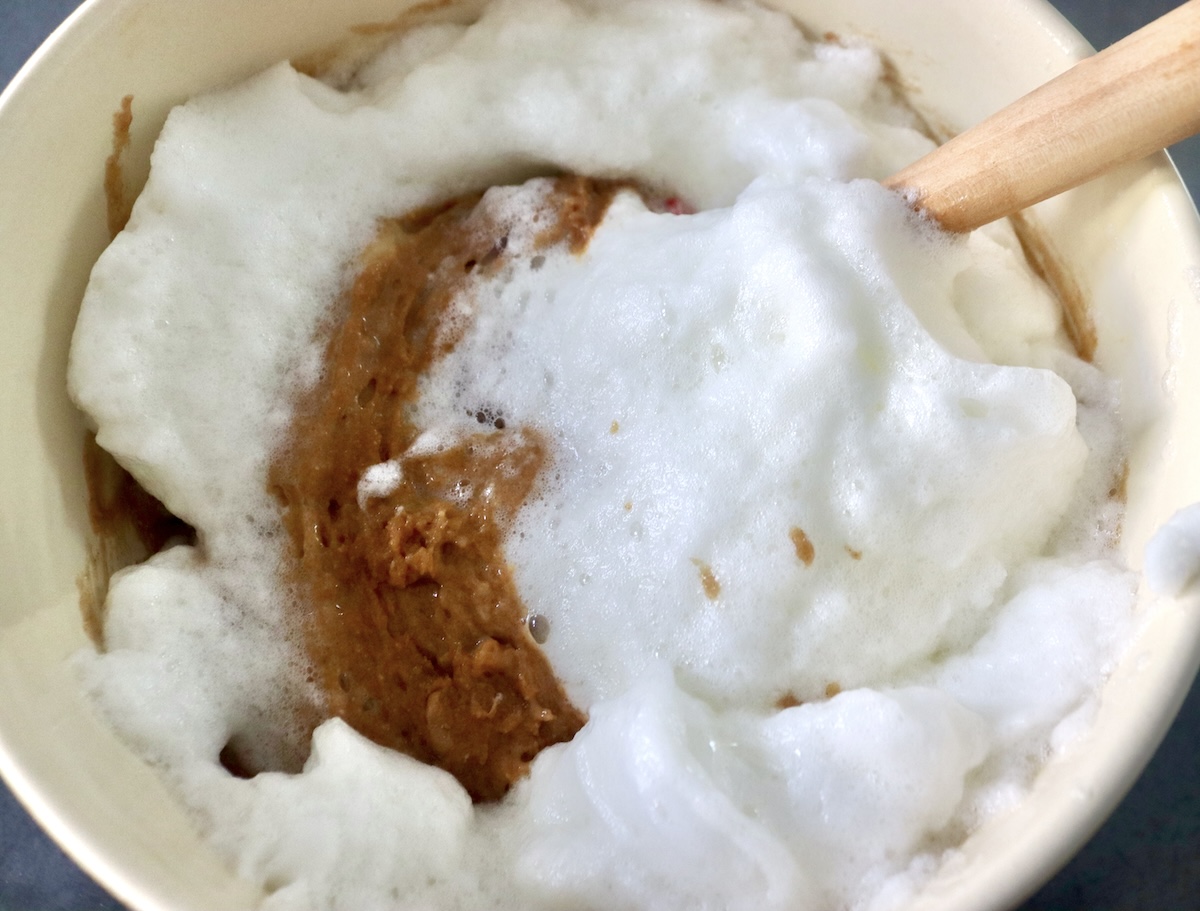 Stiff egg whites being mixed into banana peanut butter muffin batter. 