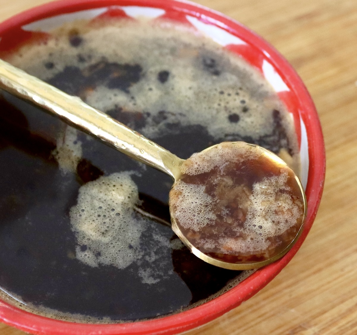 Coffee marinade for meat in a red-rimmed bowl and a gold spoon.
