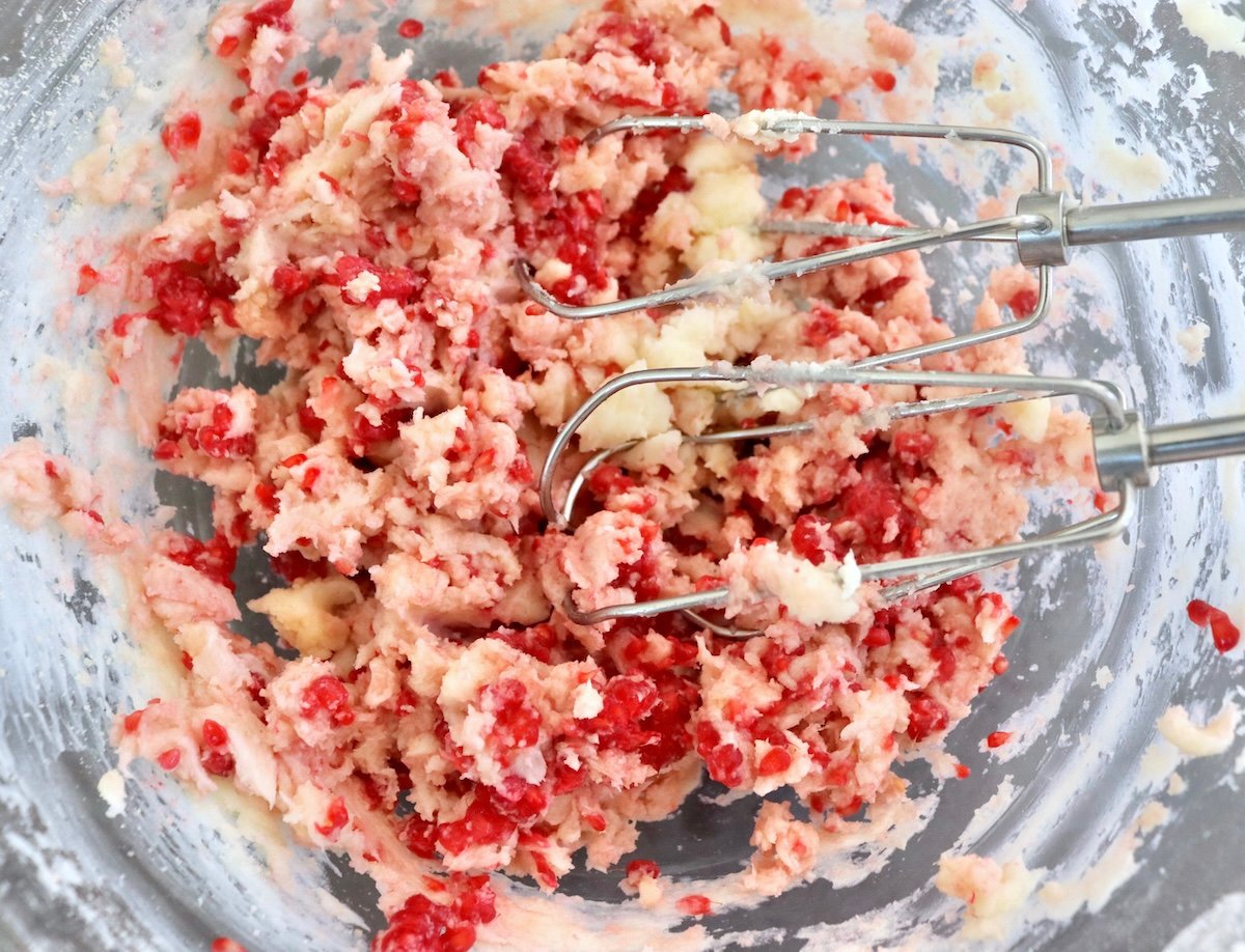 Raspberry-Chocolate-Chip-Cookies Raspberries being mixed into butter and sugar with electric an mixer in a glass bowl.