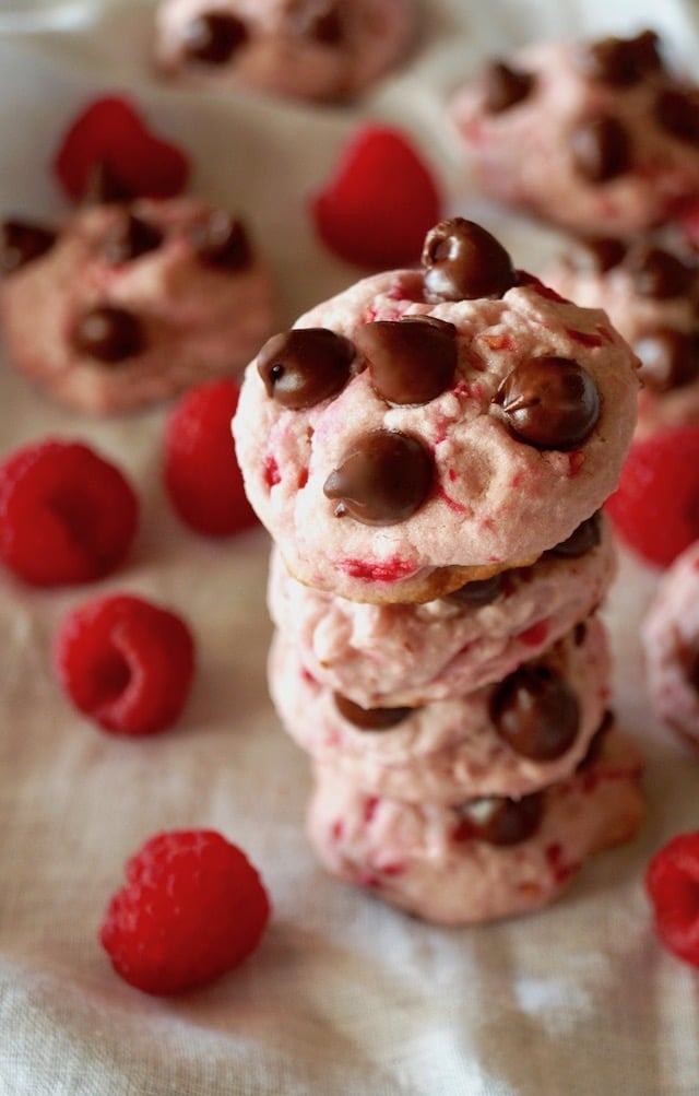 Stack of 4 Valentines' Day Raspberry Chocolate Cookies surrounded by fresh red raspberries.