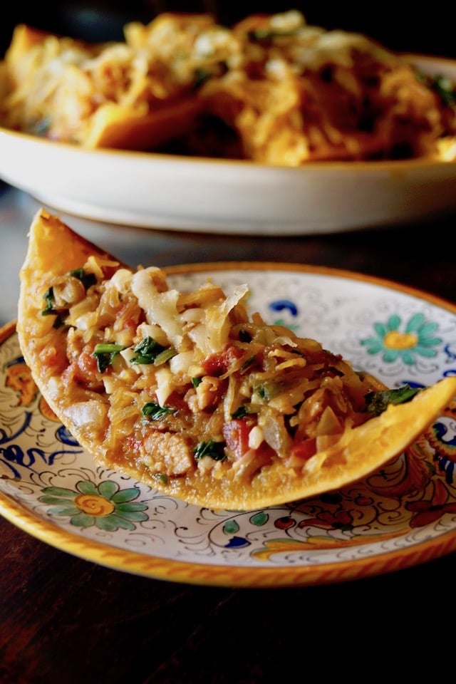 End slice of Spinach-Sausage Stuffed Spaghetti Squash, on a pretty, Italian, floral plate with greens, blues and a gold rim.