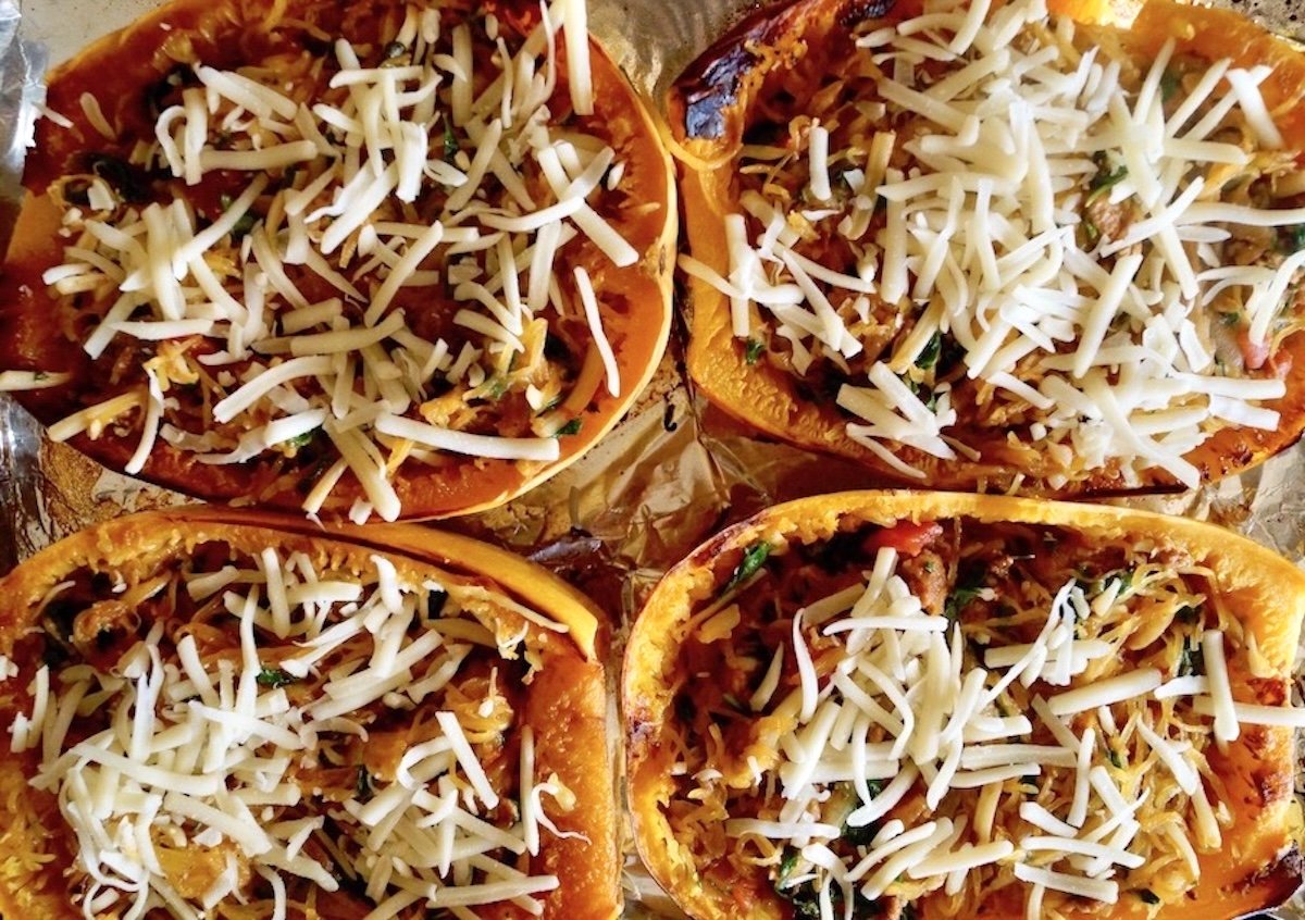 4 spaghetti squash halves filled with squash, sausage and spinach, with cheese on top,