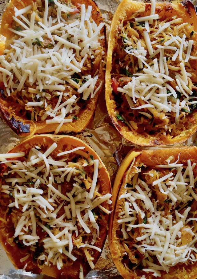 Four halves of Spaghetti squash filled with spinach, sausage and topped with cheese.