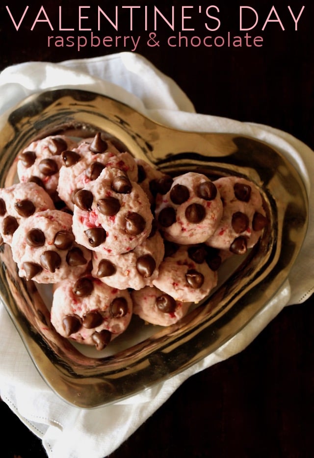 Glass heart-shaped dish on white cloth, full of Valentine's Day Raspberry Chocolate Cookies.