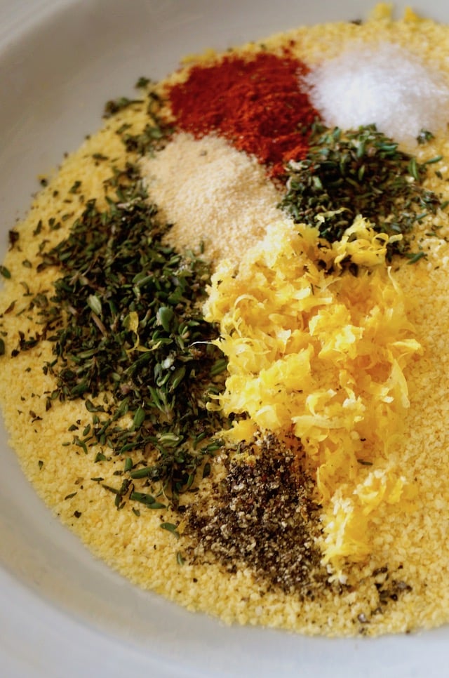 White plate of cornmeal, lemon zest, thyme and a few spices for Air Fryer Gluten-Free Lemon Fried Chicken.