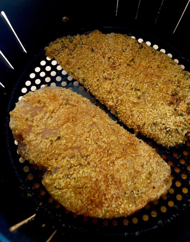 2 raw, coated chicken breasts in an air fryer basket, for Air Fryer Gluten-Free Lemon Fried Chicken.