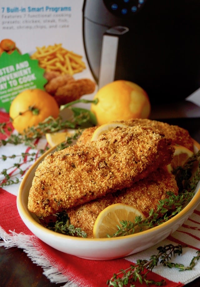 Yellow rimmed bowl full with Air Fryer Gluten-Free Lemon Fried Chicken breasts, and GoWISE air fryer box.