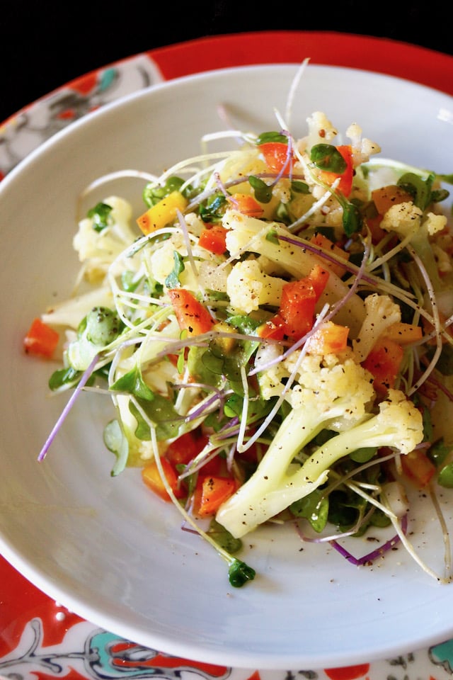 Top view of Lemon Marinated Fioretto Salad on a white plate with a red plate beneath it.