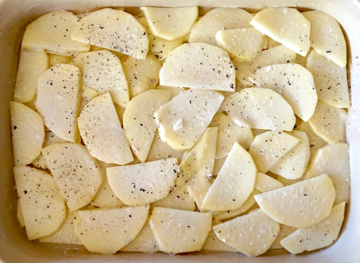 Layers of thinly sliced potato pieces in a casserole dish.
